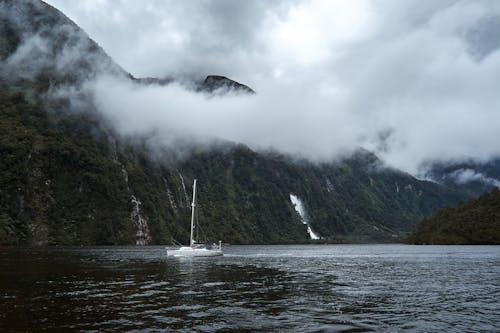 A White Boat on Body of Water Near Mountain