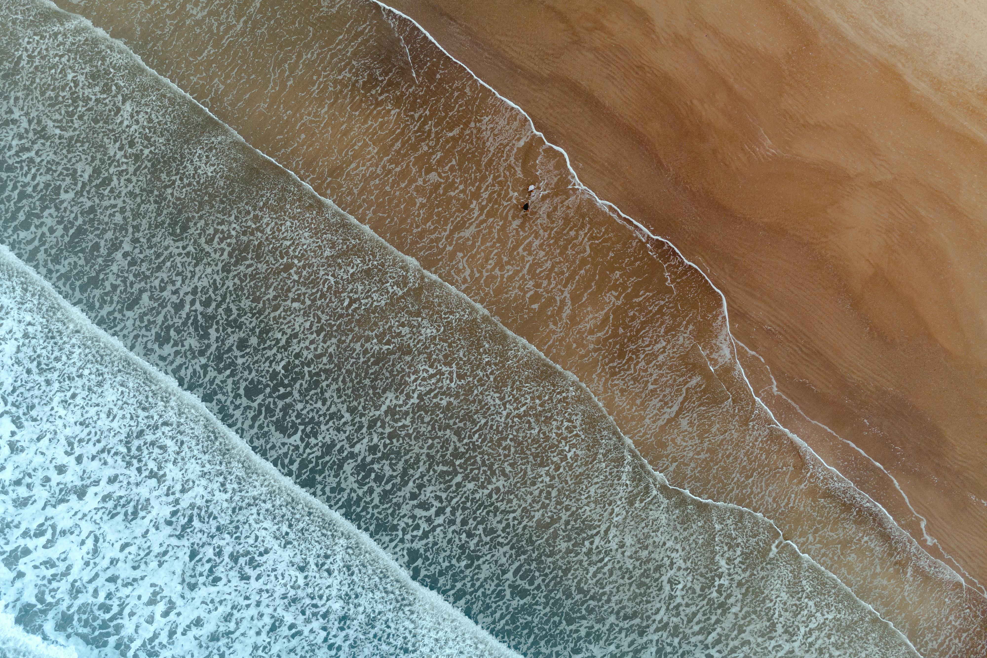 Drone aerial shot capturing the serene waves and shoreline of Galveston, Texas.