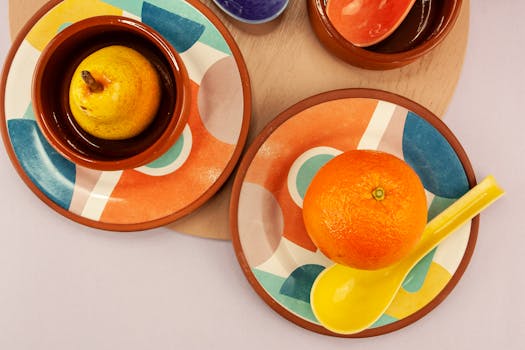 Bright and colorful composition of an orange and pear on artistic tableware, viewed from above.