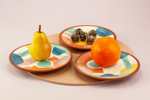 Free Vibrant still life featuring a pear, orange, and chocolate truffles on geometric plates. Stock Photo