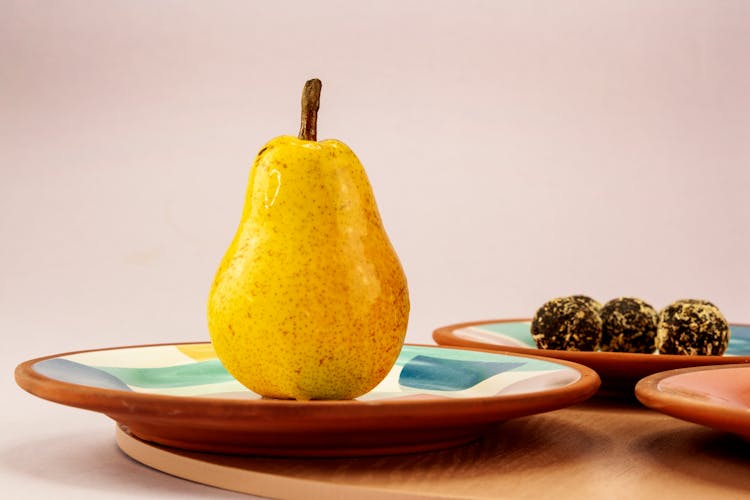 A Yellow Pear And Chocolate Truffles On Ceramic Plates