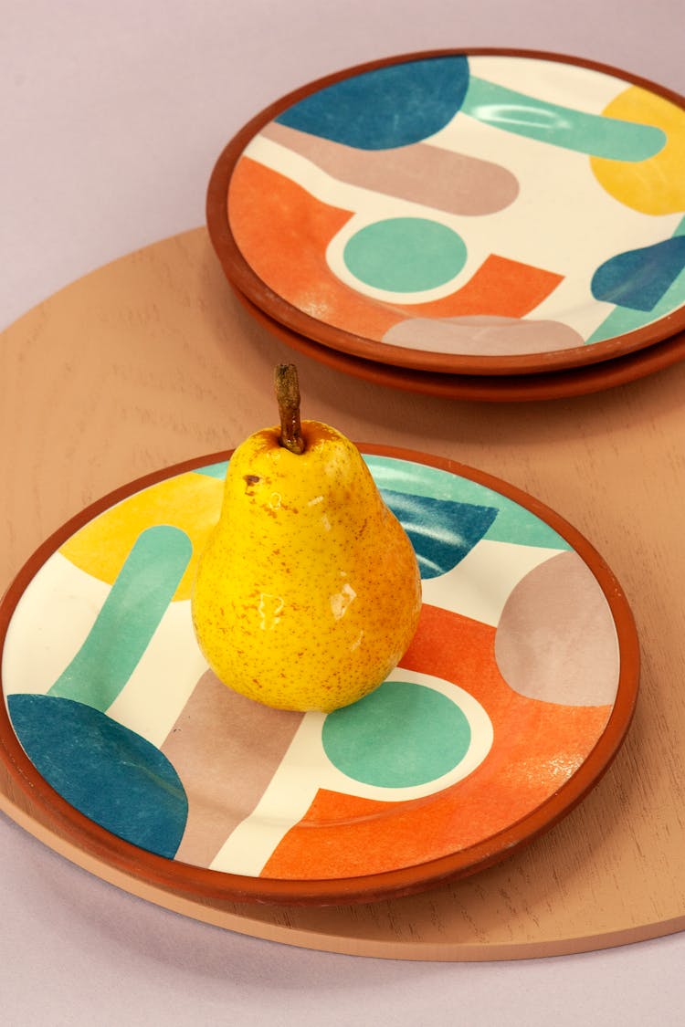 A Yellow Pear And Colorful Terracotta Plates 