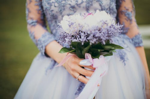 花の花束を保持している青いガウンの女性