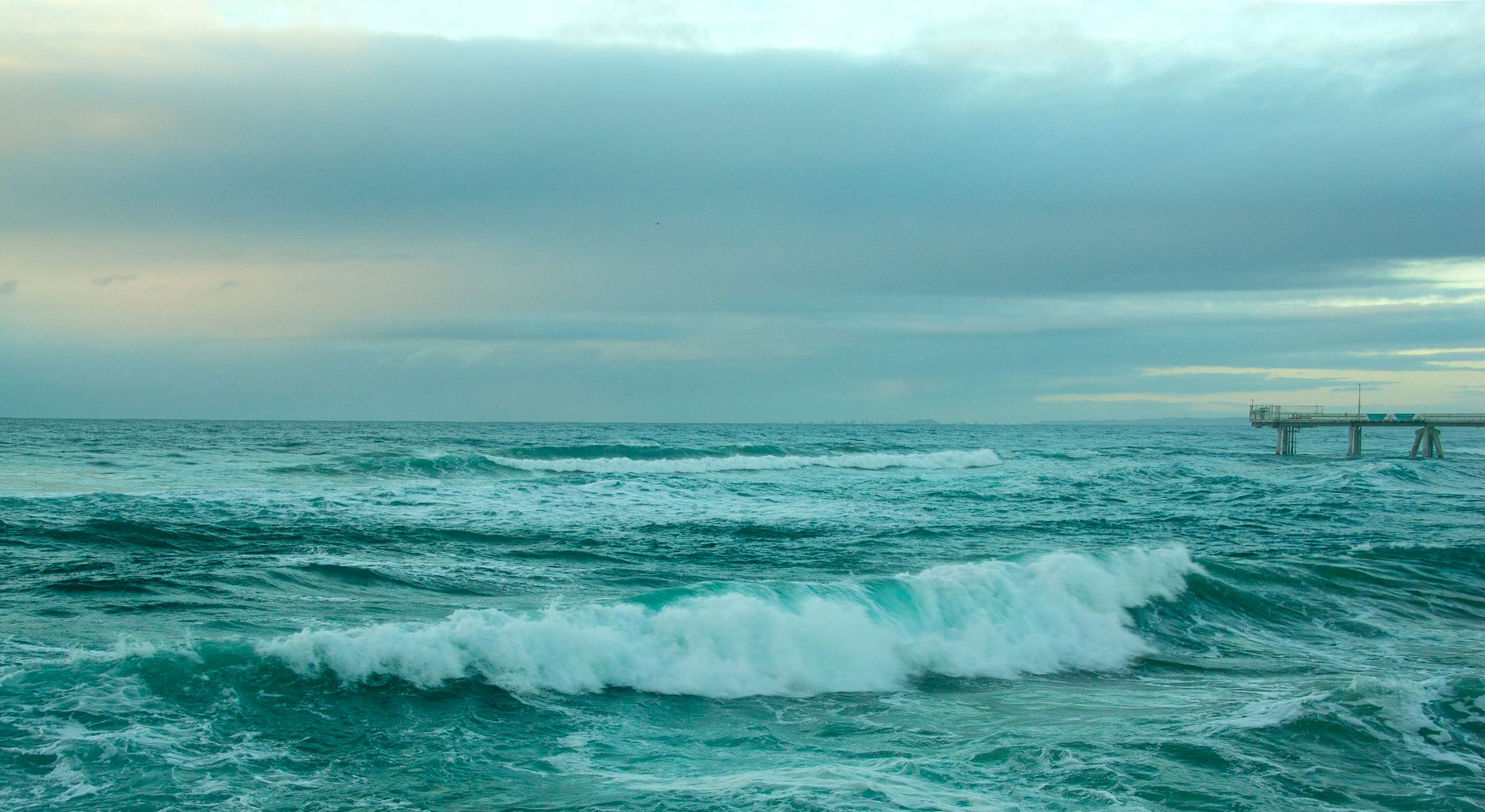 A dynamic seascape showcasing turquoise ocean waves under a cloudy sky, perfect for nature lovers.