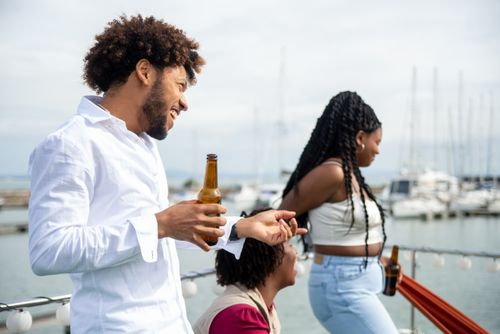 Free Group of friends having fun with beers on a boat ride in Portugal's harbor. Stock Photo