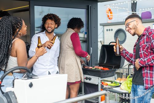 Free Group of friends having fun at an outdoor barbecue with drinks and smiles. Stock Photo