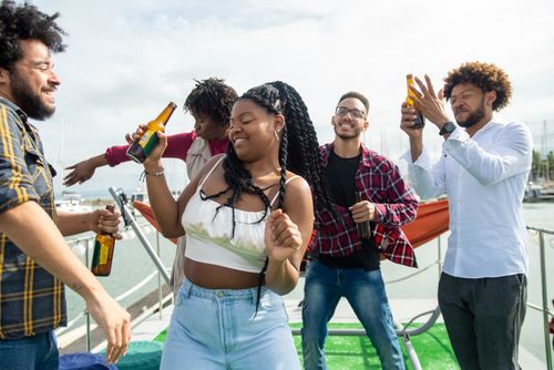 Free Friends enjoying a party on a yacht with drinks and dancing outdoors in Portugal. Stock Photo
