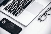 现代化工作空间的桌子上，摆放着笔记本电脑、智能手机和眼镜