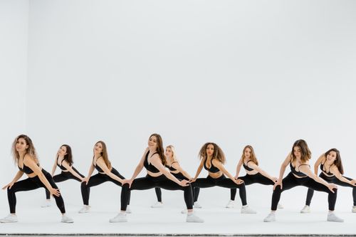 Free A dynamic group of women performing a synchronized dance routine in sportswear on a white background. Stock Photo