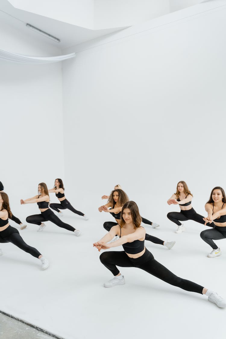 Group Of Women In Black Sports Wear Stretching Sideways