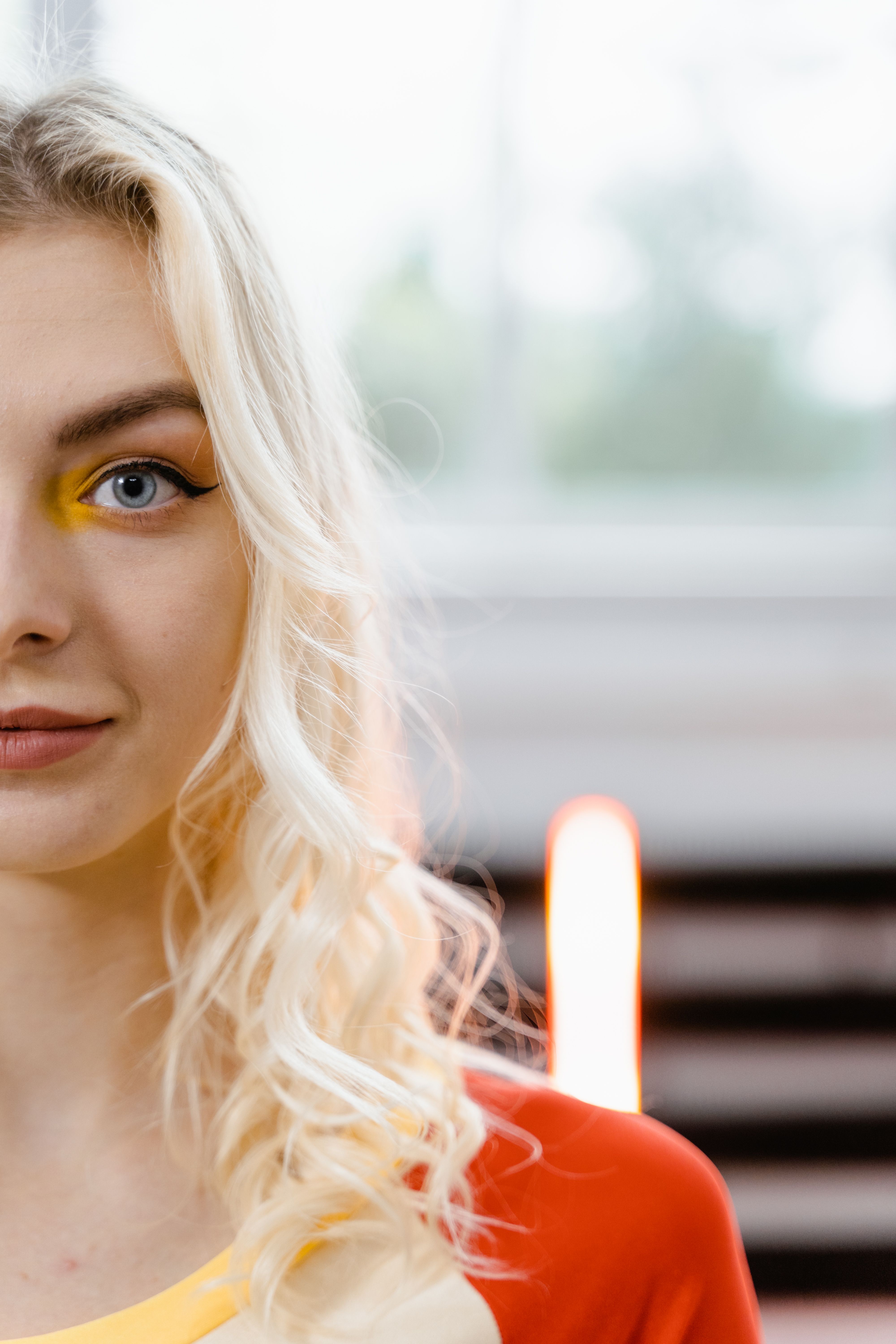 Vibrant close-up portrait of a blonde woman with colorful eye makeup.