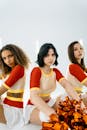 3 Women in Orange and White Shirts Sitting on White Chair