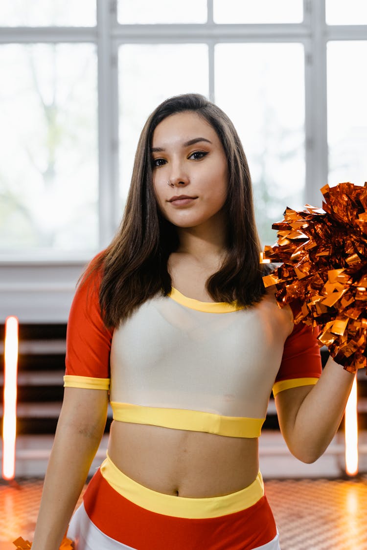 A Pretty Cheerleader Holding A Pom Pom