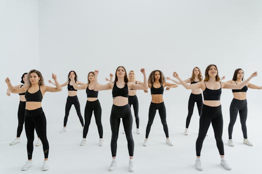 Energetic group of women in black sportswear performing dance routine indoors.