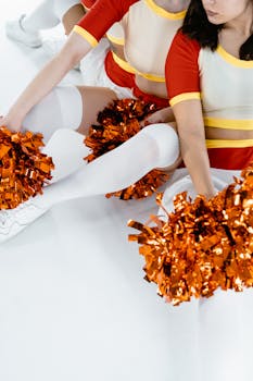 Cheerleaders in red and white uniforms energetically displaying vibrant pom poms.