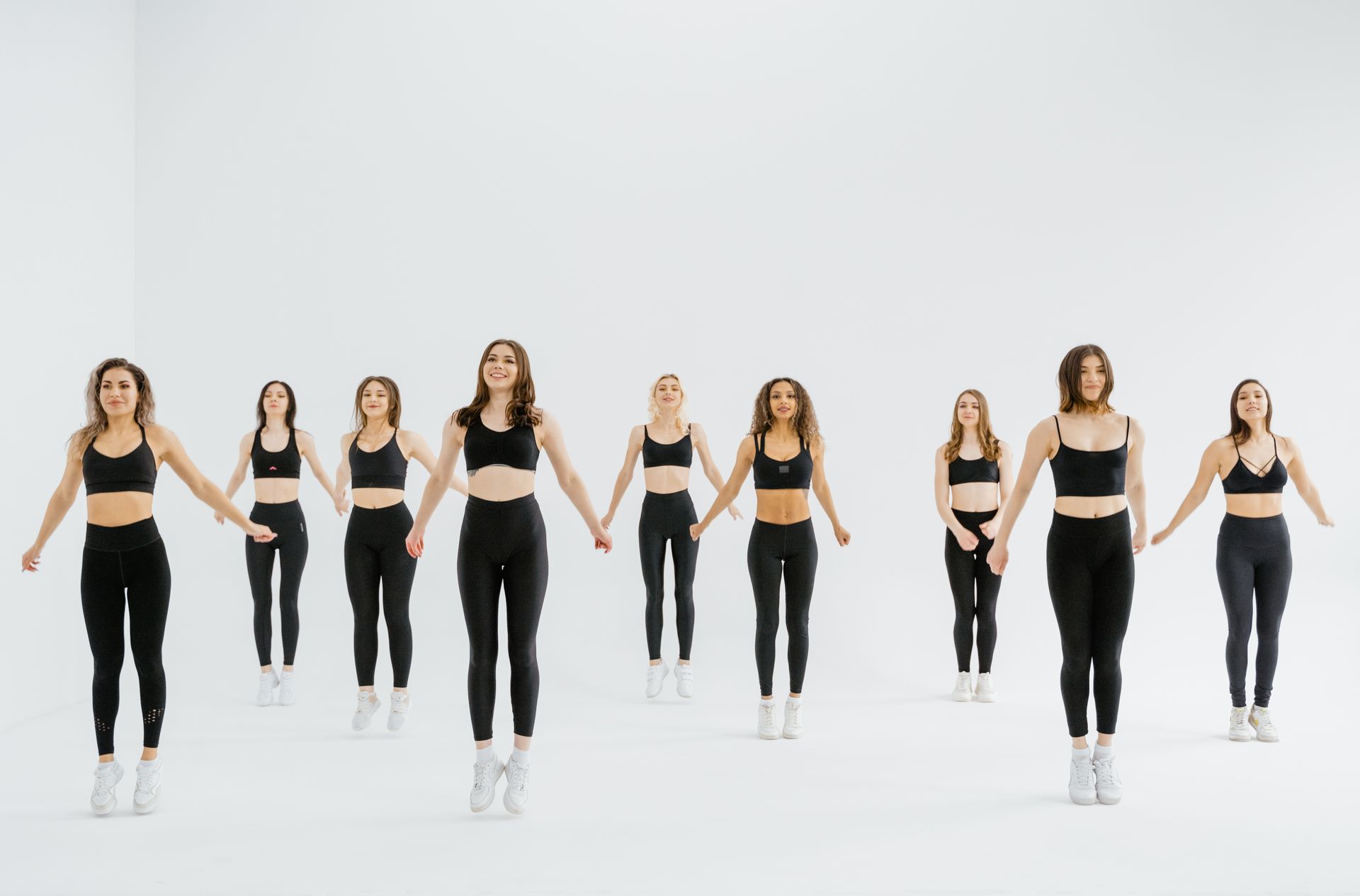 A group of women performing synchronized exercises in a bright studio setting, showcasing fitness and wellness.