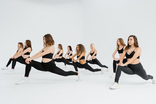 A group of women in black activewear performing lunges in a bright indoor studio, promoting fitness.