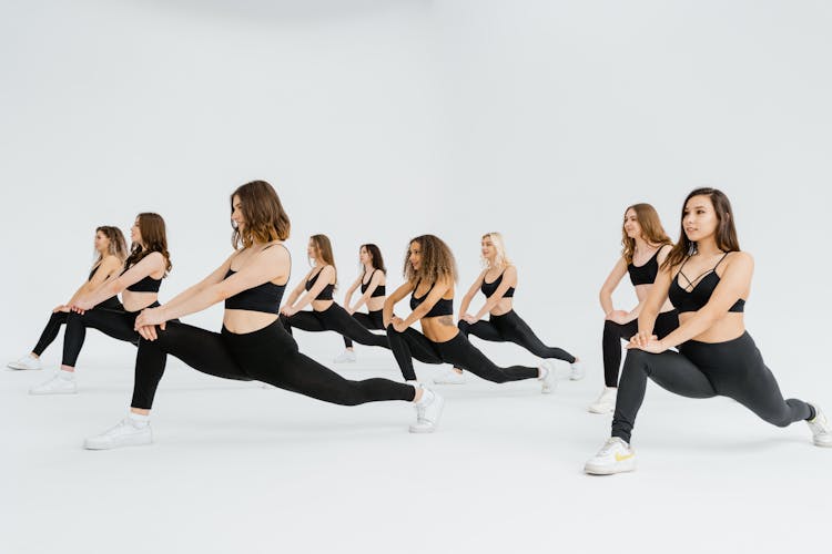 Group Of Women In Black Sports Bra And Black Leggings Doing Leg Stretching Exercise