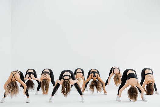 Women in activewear performing a synchronized stretching workout in a brightly lit studio.