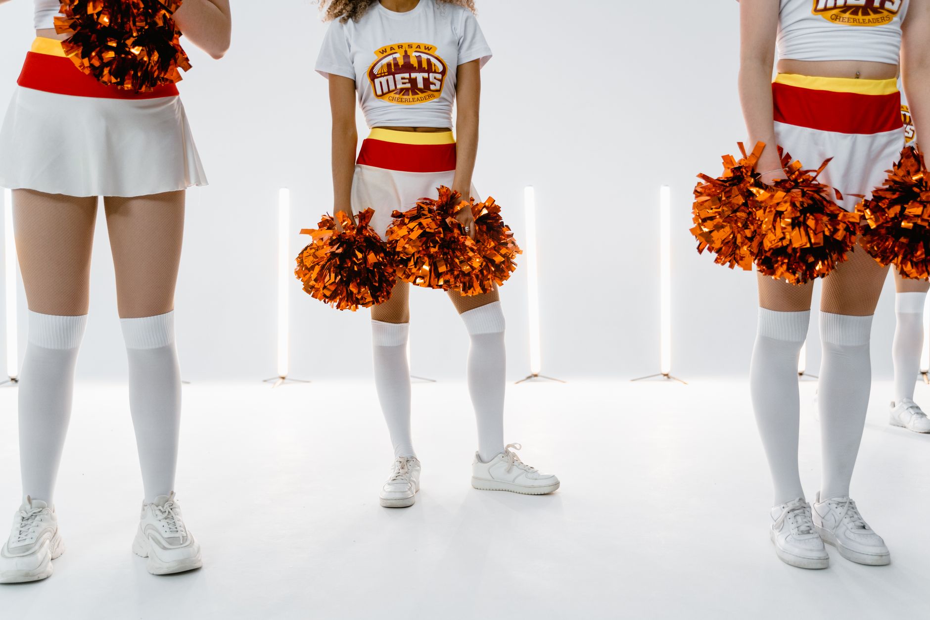 Energetic cheerleaders in uniform holding pom poms, ready for performance.