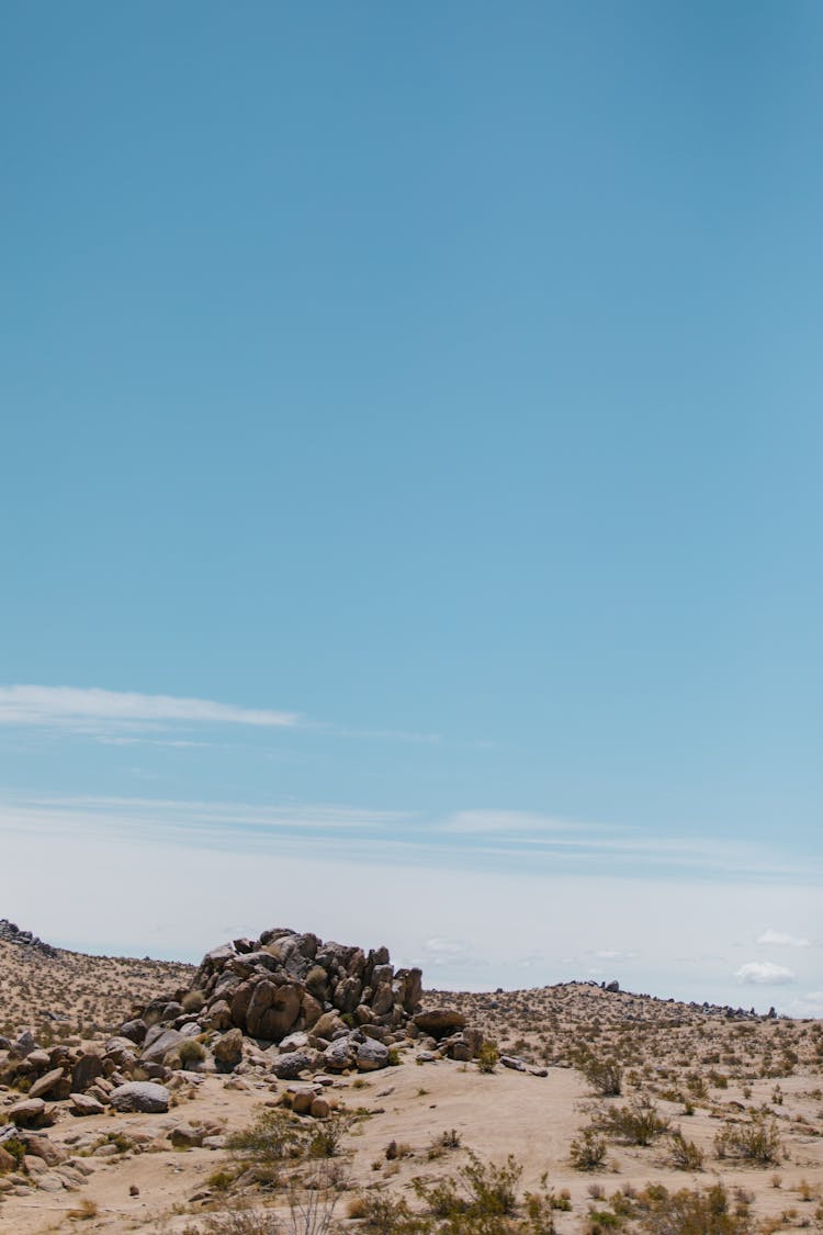 A Pile Of Brown Rocks On Brown Field Under Blue Sky