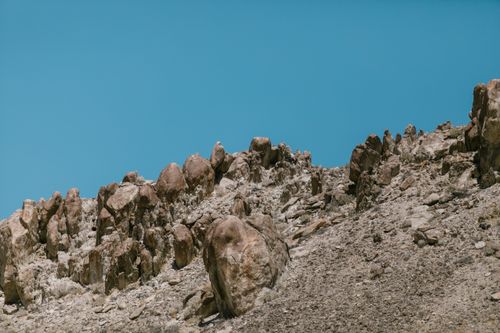 Free A barren, rocky hill with eroded formations under a clear blue sky, capturing natural scenery. Stock Photo