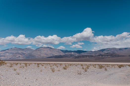 A stunning view of a rocky mountain landscape under a bright blue sky with scattered clouds.