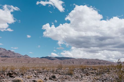 Free Vast desert landscape with rocky mountains and white clouds in Death Valley. Stock Photo