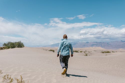 Back View of Man in Shirt Walking on Desert