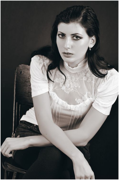 Free Stunning grayscale portrait of an elegant woman in a lace top sitting on a chair. Stock Photo