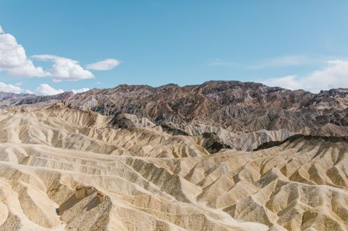 Free Captivating view of eroded landscapes and rocky mountains beneath a vibrant blue sky with clouds. Stock Photo