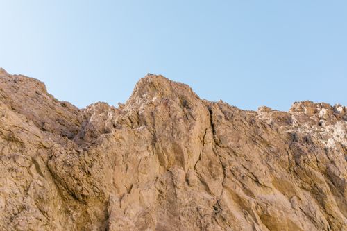 Free A detailed view of rugged rock formations against a bright blue sky, highlighting natural textures. Stock Photo