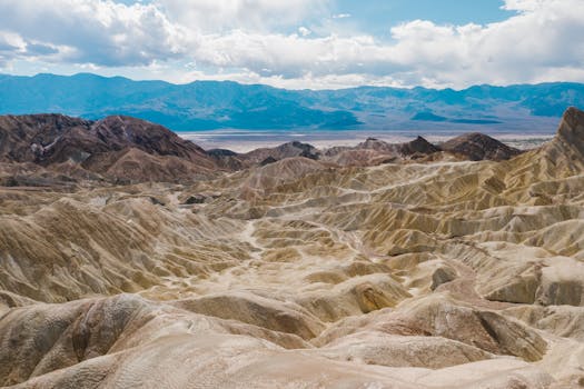 Stunning geological landscape of Death Valley National Park's desert terrain under a bright sky.