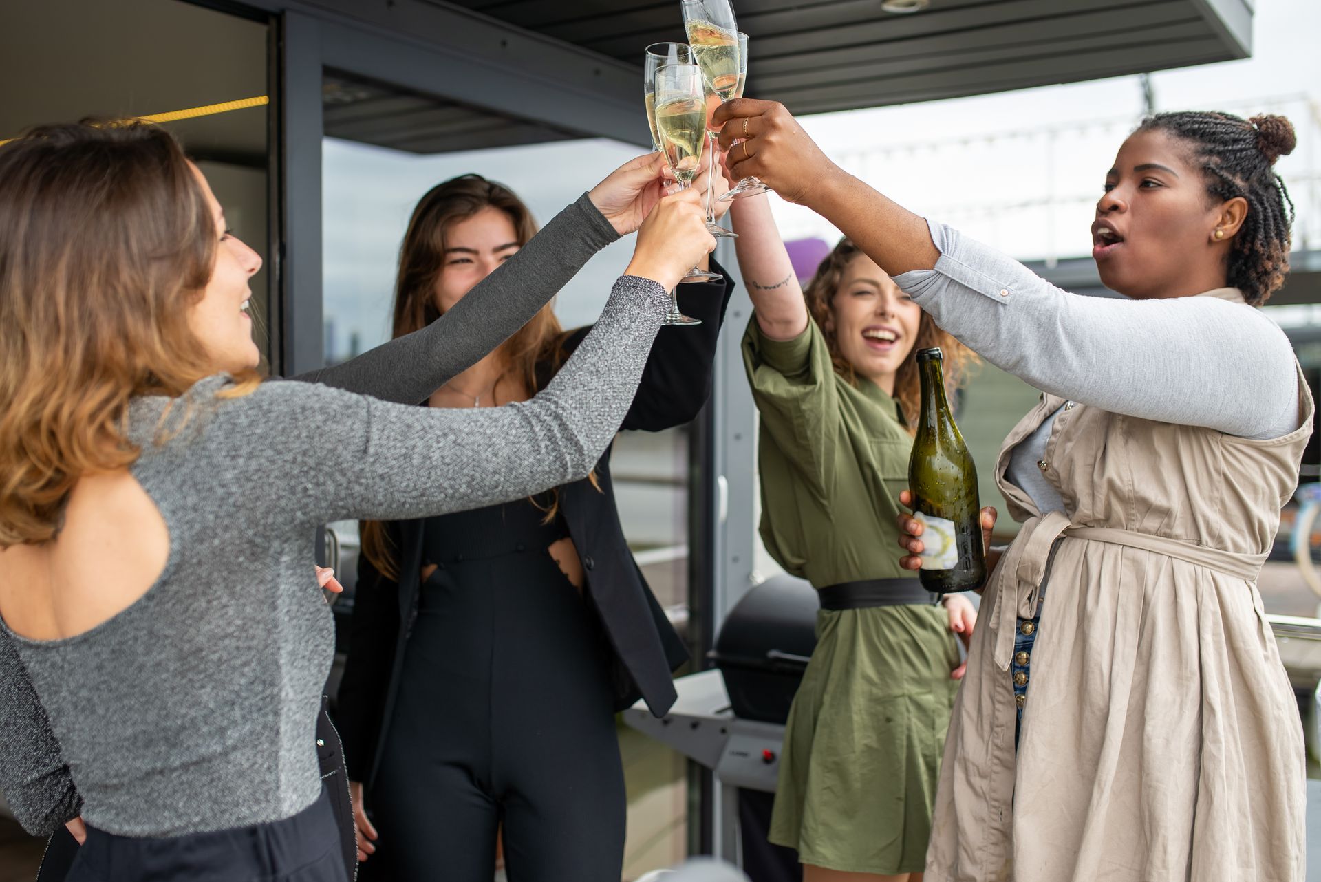 Group of friends celebrating with a toast outdoors, holding wine glasses and showing joy.