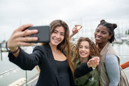 Smiling Women Holding Glasses of Wine Taking a Photo