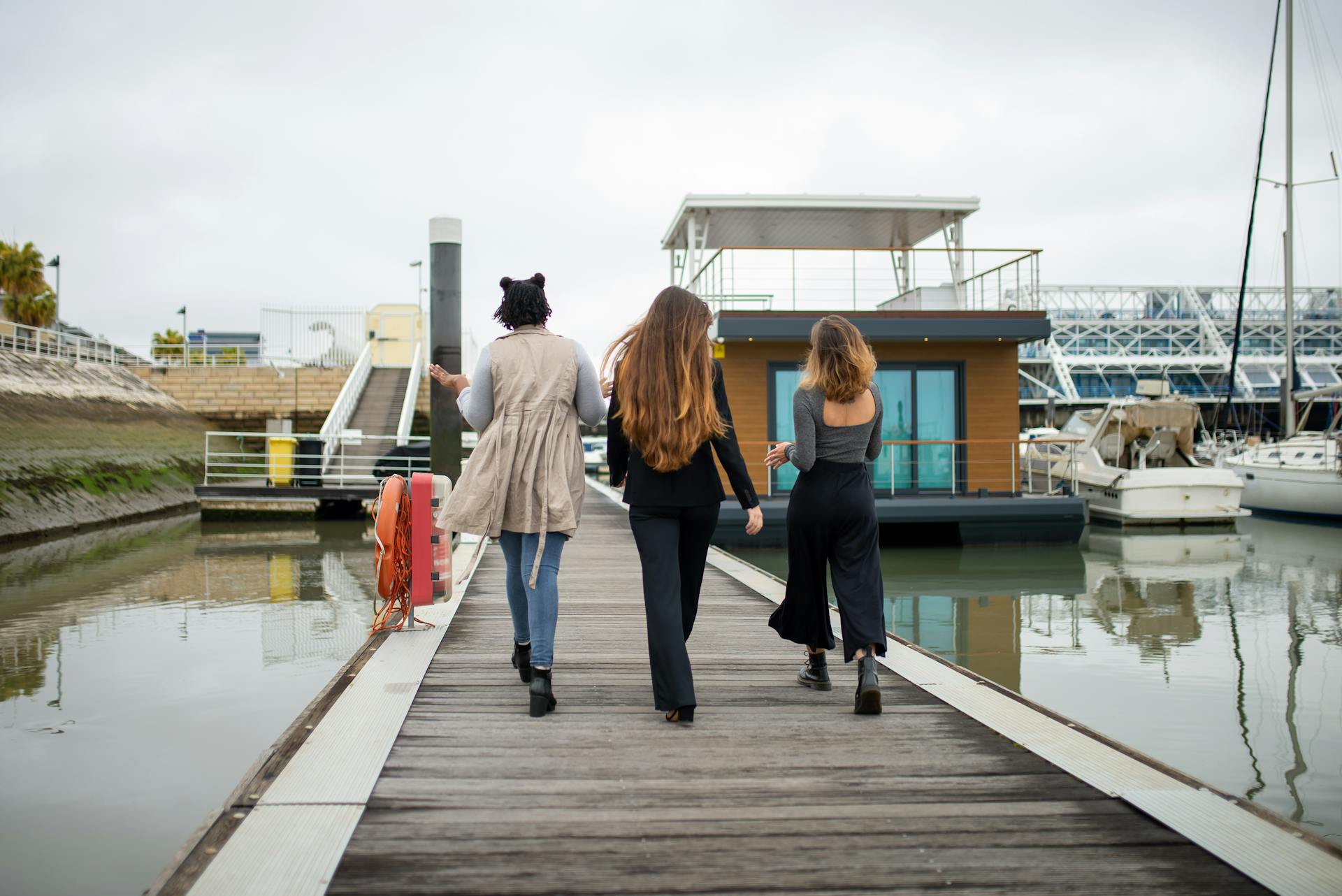 Three women walking together on a dock at a marina in Portugal.