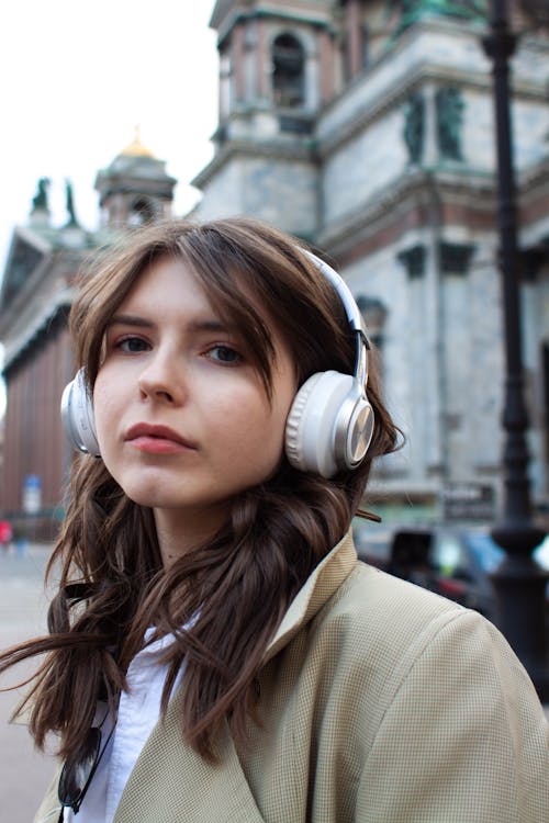 A Woman in Beige Coat Wearing Headphones