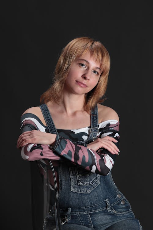 A Woman in Denim Jumper Sitting on the Chair with Her Arms Crossed