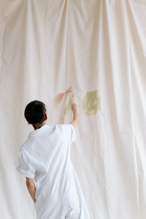 Back View of a Person Painting on White Fabric 
