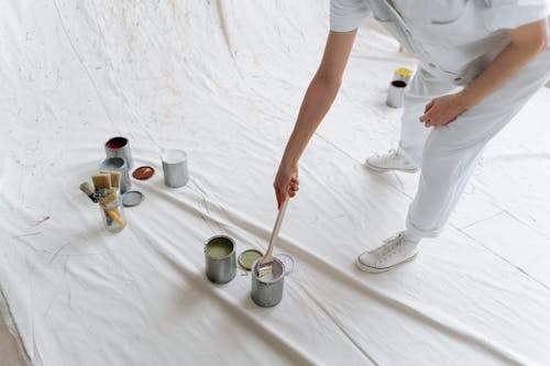 Person Standing by Cans with Paints