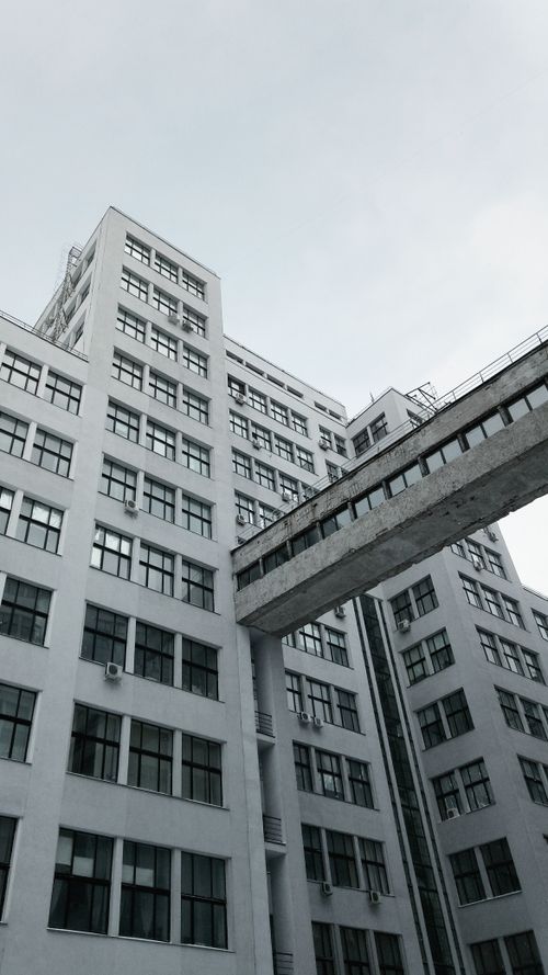 Free Low angle view of a modern high-rise building featuring a glass exterior and connecting walkway. Stock Photo