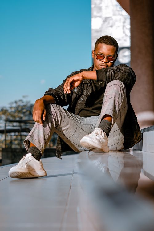 Free Stylish man in sunglasses sitting on outdoor steps, radiating confidence and style. Stock Photo