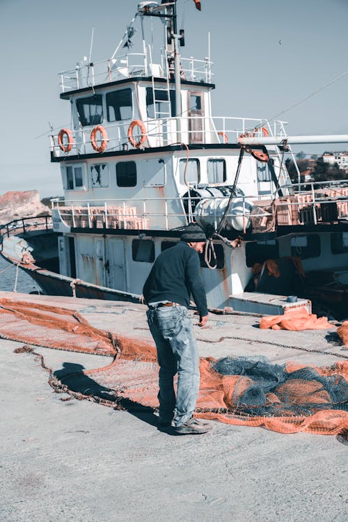 Free Person in Blue Denim Jeans Standing Near Fishing Net Stock Photo