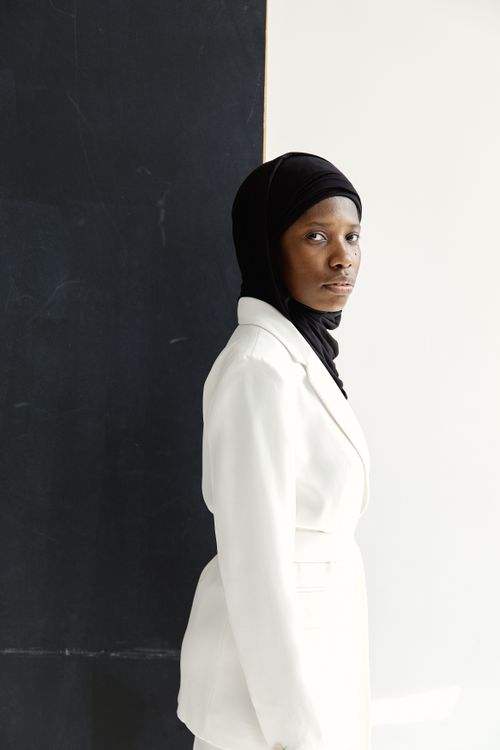 Free Stylish portrait of a woman in a hijab and white suit against a minimalist background. Stock Photo