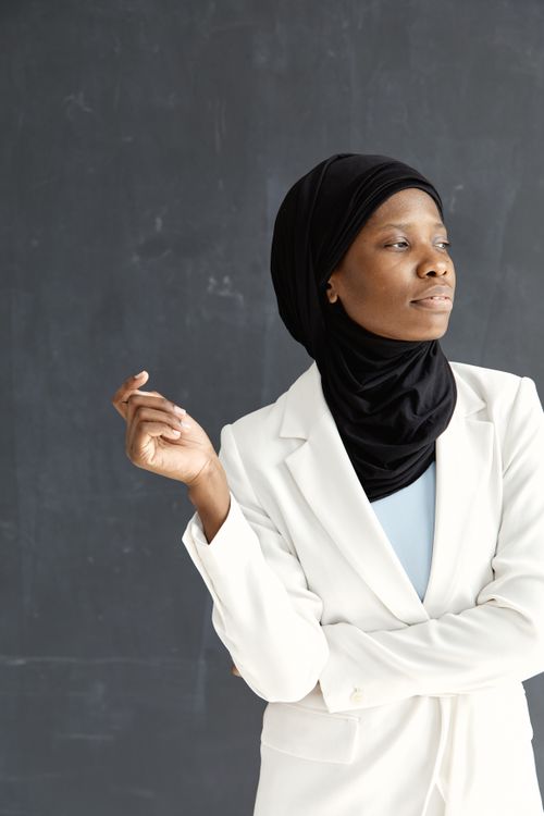 Free Portrait of a confident woman wearing a hijab and a white blazer, looking thoughtful. Stock Photo