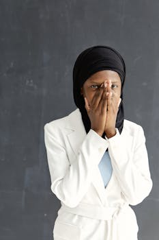 Intriguing portrait of a woman wearing a hijab and white blazer, set against a textured backdrop.
