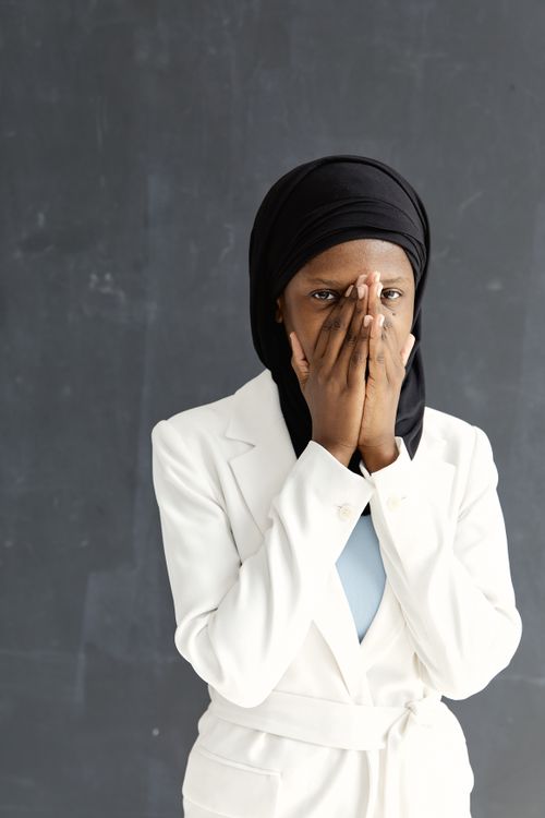Free Intriguing portrait of a woman wearing a hijab and white blazer, set against a textured backdrop. Stock Photo