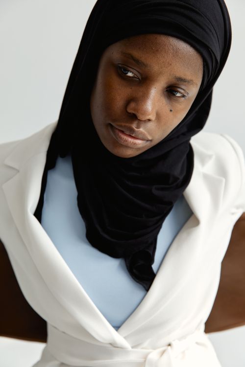 Free Thoughtful portrait of a woman in a black hijab and white outfit. Stock Photo