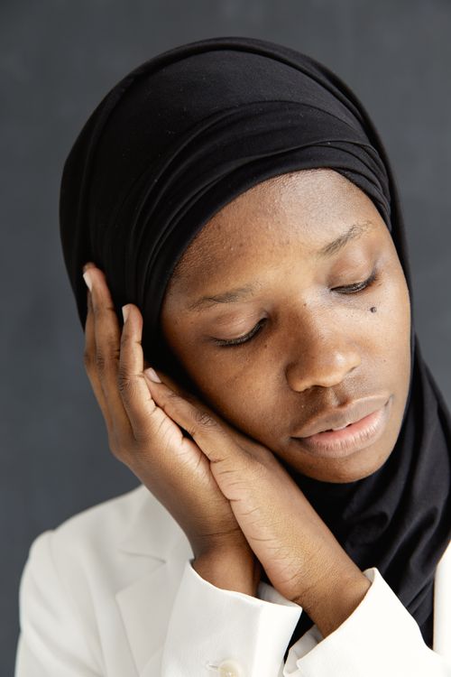 Free A serene portrait of an African woman in a black hijab resting her head on her hands. Stock Photo