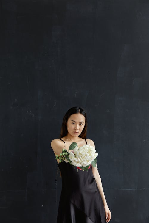 A Woman in a Black Dress Holding Flowers